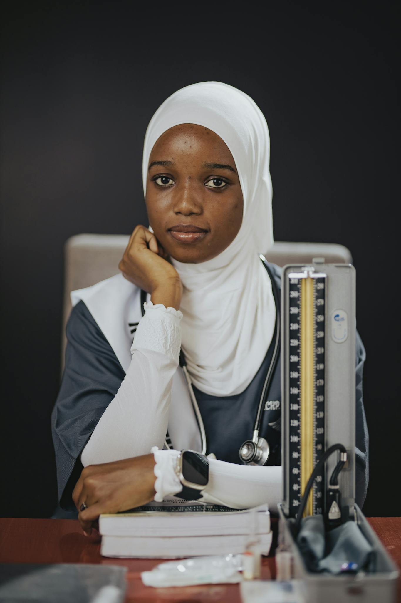 Portrait of a female medical student wearing a hijab, sitting with medical tools.